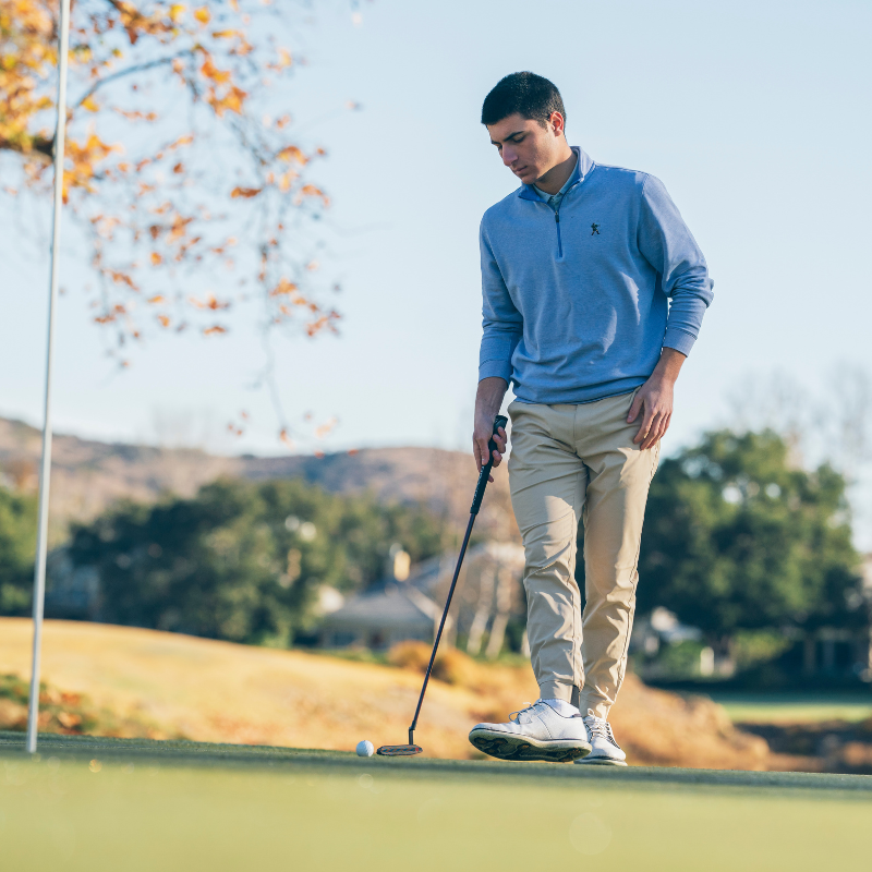 A person is playing golf on a course, preparing to putt.