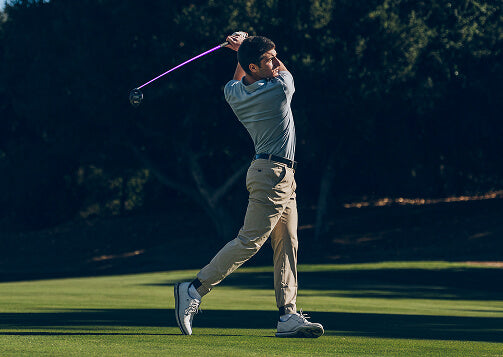 A person swinging a golf club on a golf course.